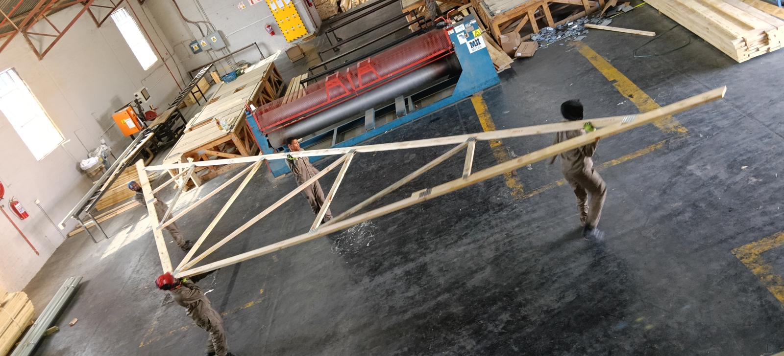 A long-span roof truss being moved across the factory floor