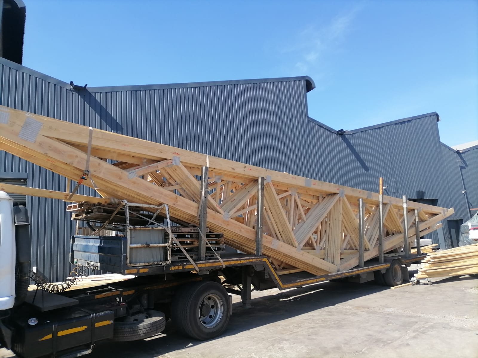 A long-span timber roof truss loaded on a Truss Master lowbed trailer ready for delivery